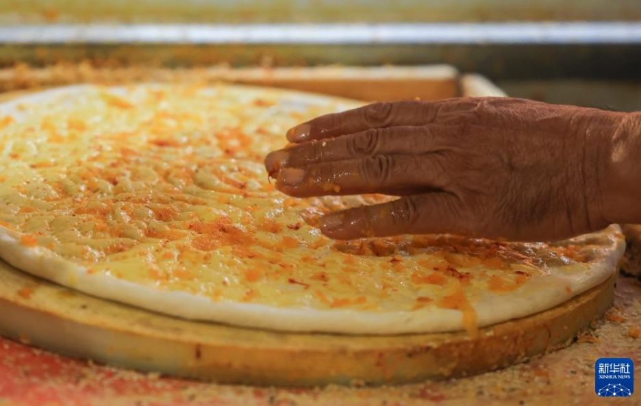 ナンの生地に香辛料をトッピングする様子（7月22日撮影?王菲）。