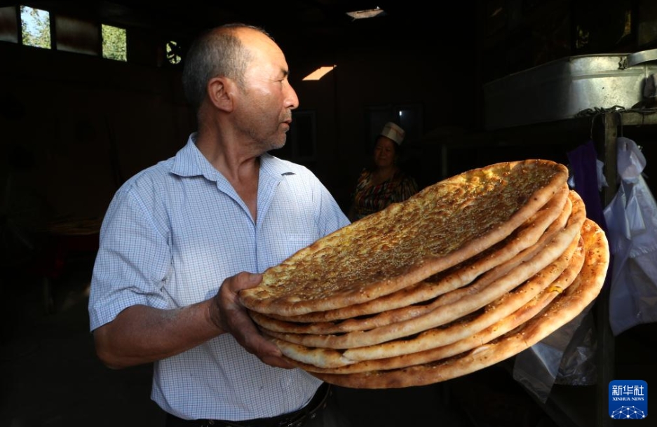 新疆庫車市で、焼き上がったナンを店先に運(yùn)び、販売する準(zhǔn)備をする熱西堤さん（7月22日撮影?耿馨寧）。