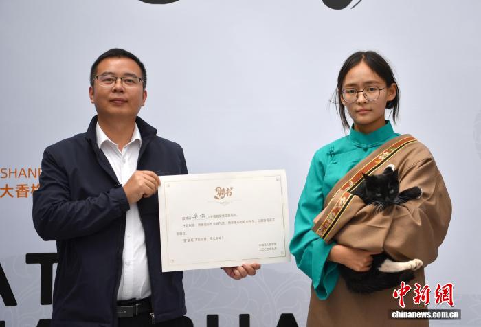 「郷城貓局長」の任命狀を手にしたゲストと「貓局長」に選ばれた卓喵（9月20日撮影?王磊）。