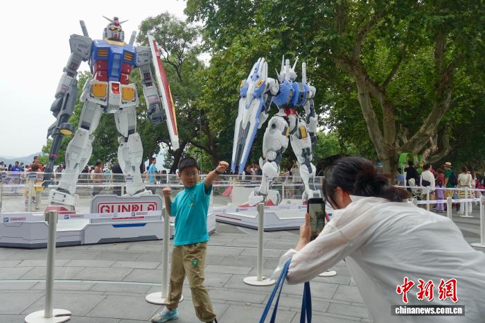 ガンダム立像をバックに寫真を撮影する観光客（9月21日撮影?銭晨菲）。