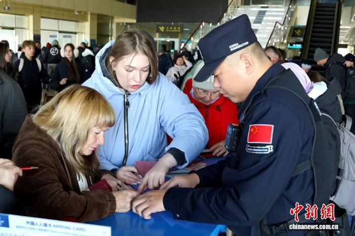 黒河國(guó)境検査所で中國(guó)に入國(guó)する観光客に入國(guó)カードの書(shū)き方を教える警官（撮影?張鈞凱）。