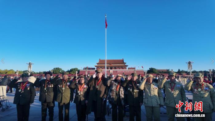 10月26日、天安門広場に掲げられた國旗の前で記念寫真を撮影する抗米援朝出國作戦に參加した老兵（撮影?劉子衿）。