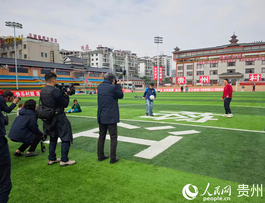 貴州省榕江県の「村超」の試合會(huì)場(chǎng)で選手と交流?取材するメディア団（撮影?龍章楡）。