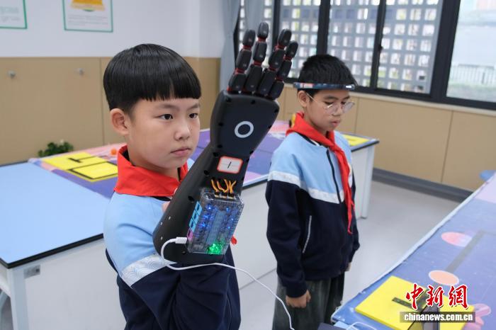 真剣な表情でロボットアームを操作する児童（11月12日撮影?曹丹）。