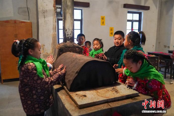 黒竜江省鉄力市の透竜景勝地で、ストーブの傍で火にあたる子供（11月29日撮影?趙宇航）。