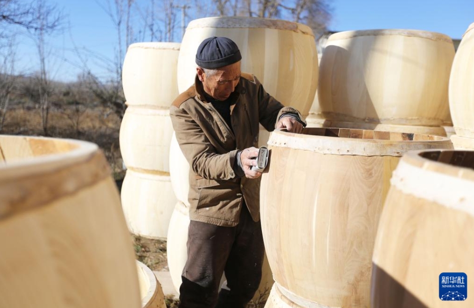 牛革太鼓の表面をやすりがけする伝統(tǒng)工蕓職人の周天成さん（11月27日撮影?王克賢）。
