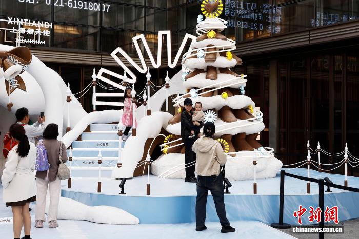 上海新天地の店舗前で、冬のテーマ裝飾を背景に記念寫(xiě)真を撮影する観光客（12月1日撮影?殷立勤）。