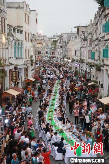 4月13日夜、海口市の騎樓老街に並べられたテーブルで食事をする人々（撮影?馮恵）。