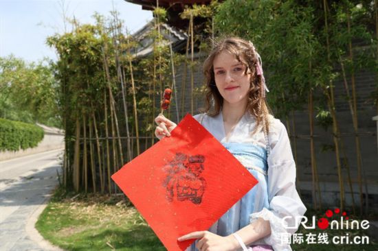 「福」と書かれた赤い紙を持つルーマニアのネット有名人（撮影?賈親親）。